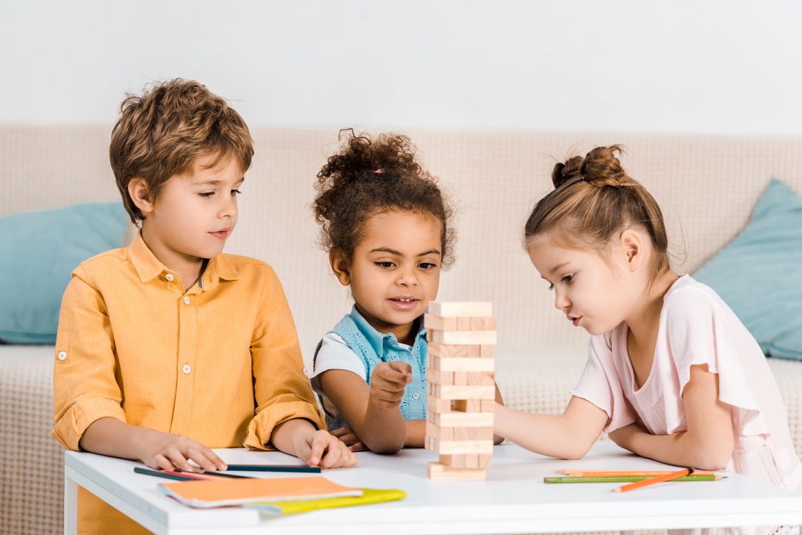 one young boy and two young girls playing with Jenga blocks