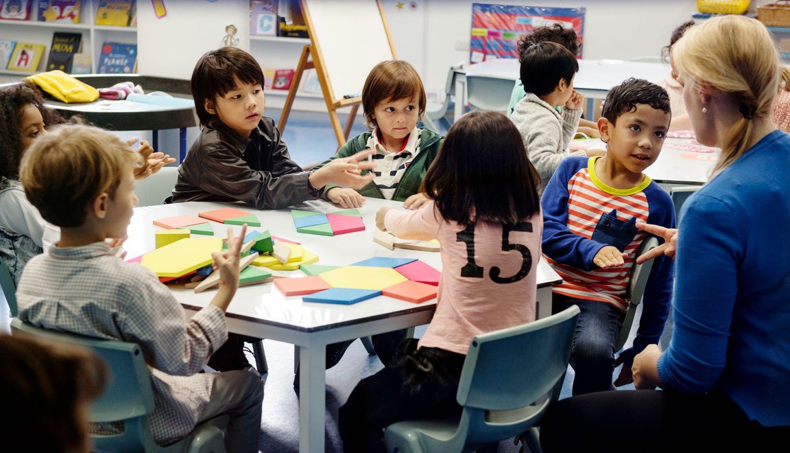 kindergarteners sitting at table with teacher